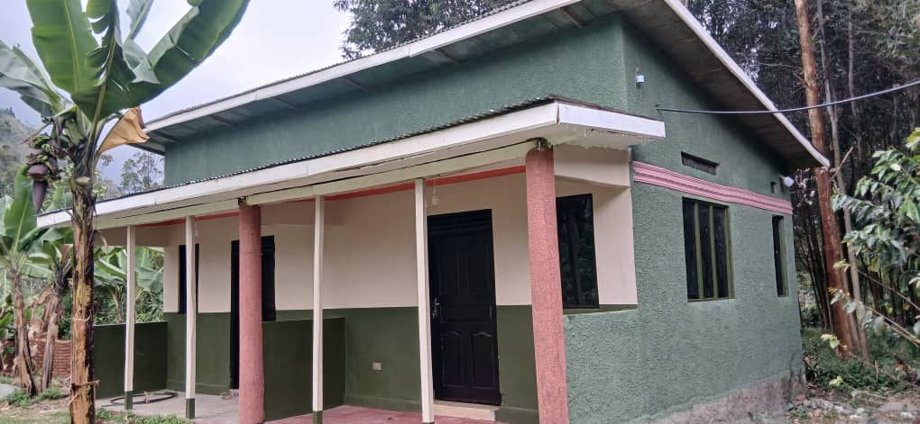Green guest room building with a covered veranda at Mihunga Campsite